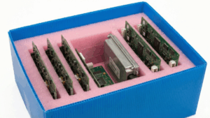 Caja azul abierta con inserto de espuma antiestática rosa y múltiples tarjetas de circuito y módulos electrónicos encajados a medida